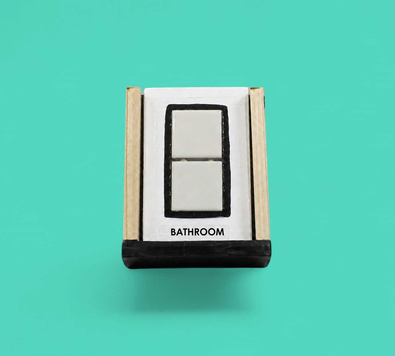 This image depicts a standard white tactile card that is 4 by 6 inch size and displays two white ceramic tiles square centered between a black rectangular outline, labeled on the bottom is the word "Bathroom"