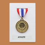 The Award symbol is circular gold plated medal embedded in the center position on a white background with red, white, blue ribbon fabric at the top of the award medal. Labeled 