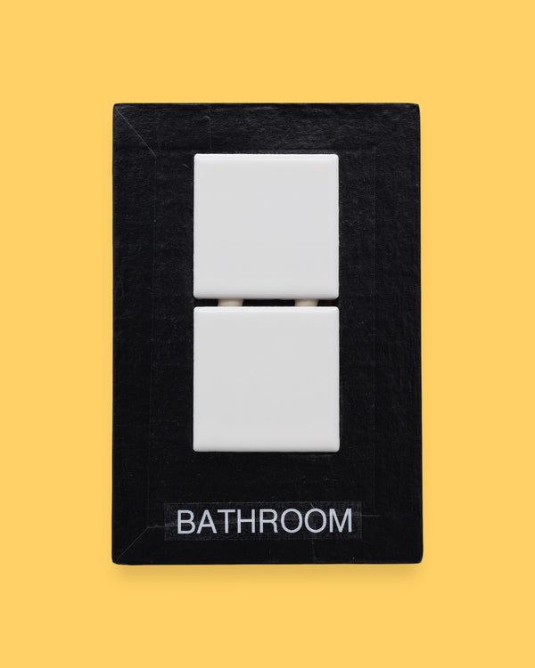 The Bathroom-tile symbol has two square, white, ceramic tiles are embedded vertically in the center of the card. Labeled "Bathroom" in black font on white backing. The background of the symbol is white.