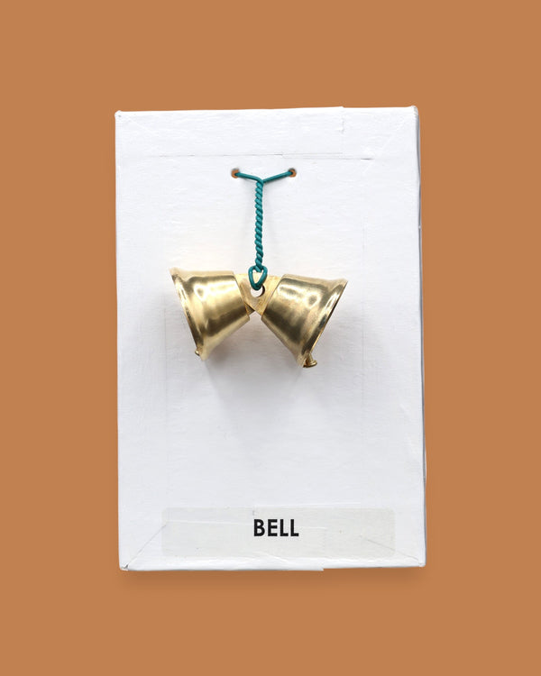 The Bell with two small golden-plated metal bells embedded sided by side with a green interlocked wire holding the bells together. Labeled "Bell" in black font at the bottom of symbol on white backing. The background of the symbol is white.
