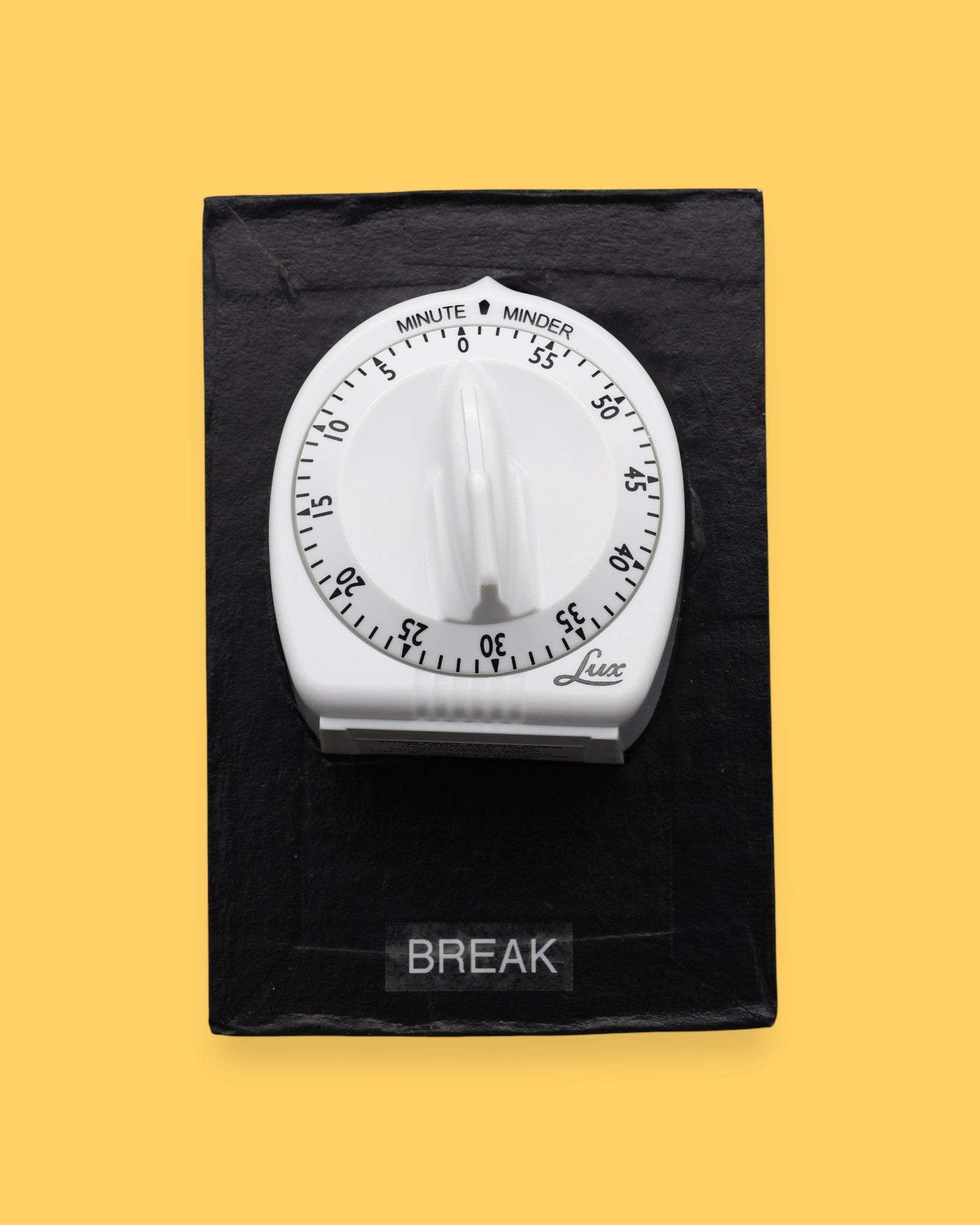 The Break Kitchen Timer symbol has a 3D shaped white kitchen timer with black numbering with a movable dial that is embedded in the center of the card with white backing. Labeled "Break" in white font at the bottom of symbol on clear backing. The background of the symbol is black.