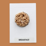 The Breakfast Cereal Box symbol has a small cereal box is embedded in the center of the card, with the option to customize the card using a with white backing for increased contrast. The color of the box may vary. Labeled "Cereal" in black font at the bottom of symbol on white backing. 