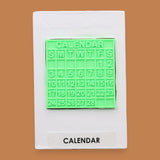 The Calendar symbol with a 3D PLA printed filament in lime green a small monthly calendar piece embedded in center. Labeled "Calendar" in black font at the bottom of symbol on white backing.