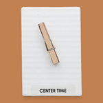 The Center Time symbol consists of a wooden clothespin embedded vertically in the center. Labeled "Center Time: in black font on white backing at the bottom of the symbol. The background of the symbol is white. 
