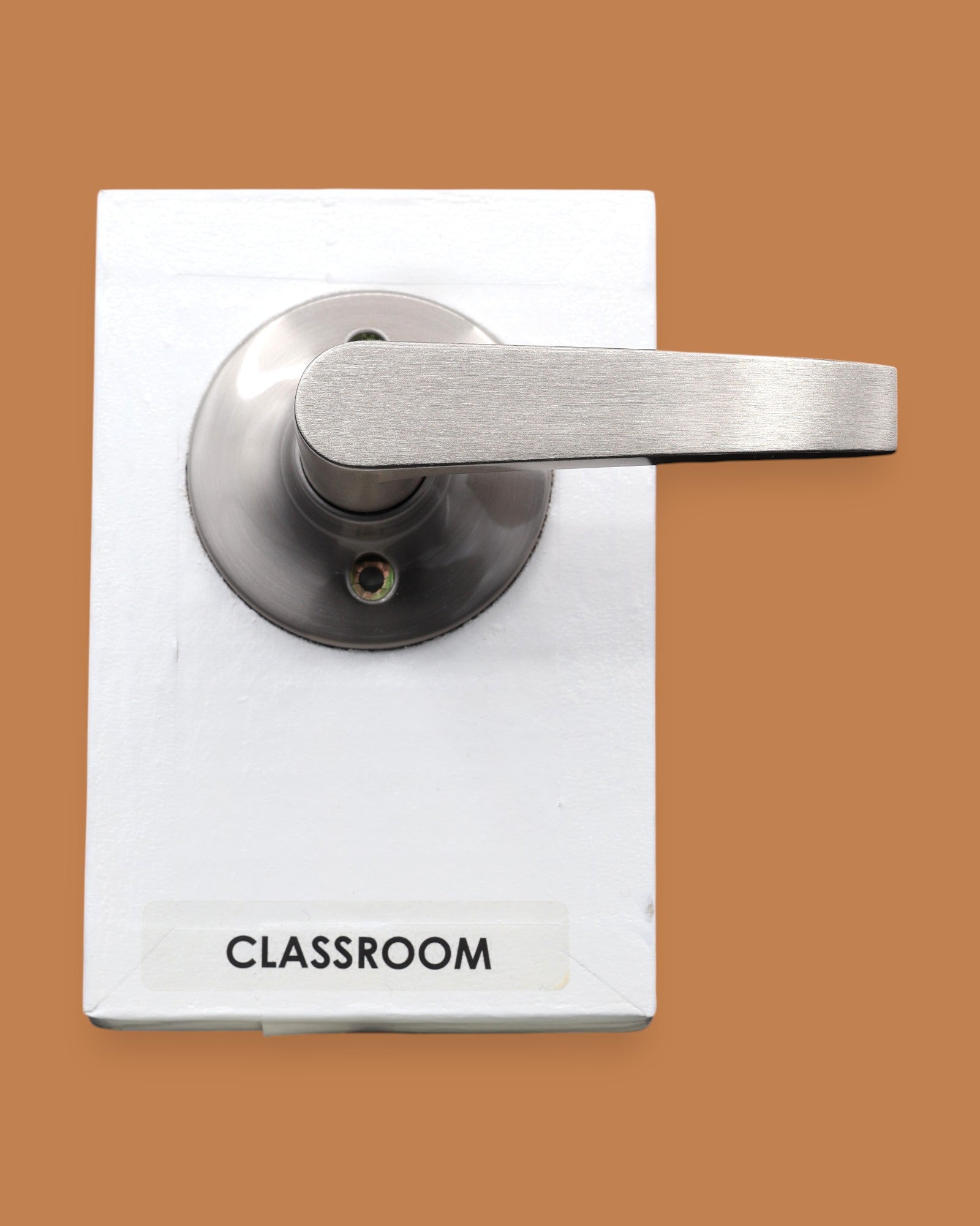 The Classroom symbol with a pushable metal door lever embedded horizontally. Labeled "Classroom" in black font on white backing at the bottom of the symbol. The background of the symbol is white. 