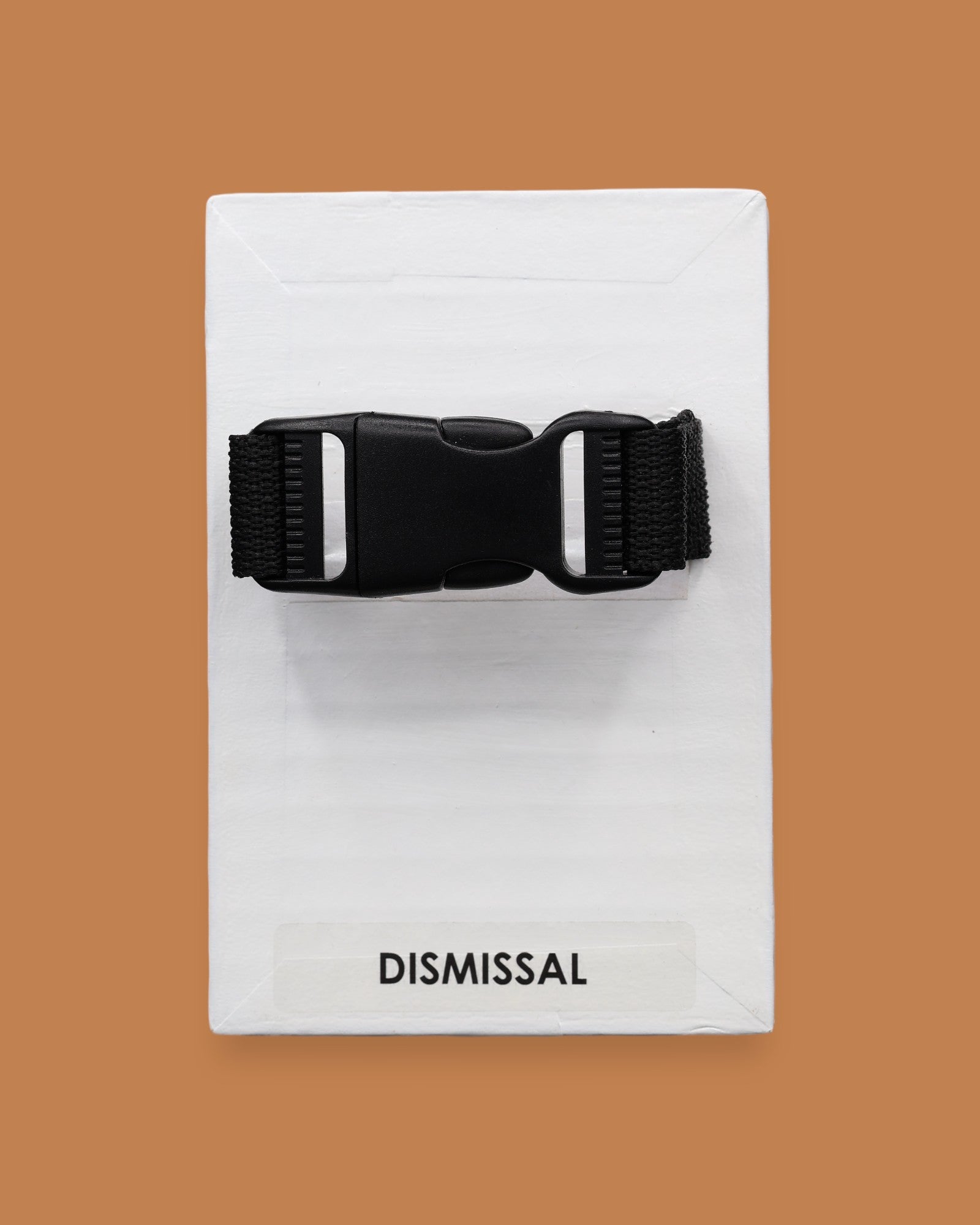 The Dismissal symbol with a black closed buckle embedded in the center horizontally. Labeled "Dismissal" in black font on white backing. The background of the symbol is white. 