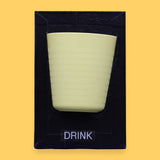 The Drink symbol has a light green cup with horizontal ridges embedded. Labeled "Drink" in black font and white backing at the bottom of symbol. The background of the symbol is black.