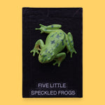 The Five Little Speckled Frogs symbol is a 3" frog toy figure embedded in the center of the cue on top of a recessed wooden base. These plastic frogs come in a variety of designs and colors. The background of the card is black.