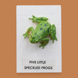 The Five Little Speckled Frogs symbol is a 3" frog toy figure embedded in the center of the cue on top of a recessed wooden base. These plastic frogs come in a variety of designs and colors. The background of the card is white.