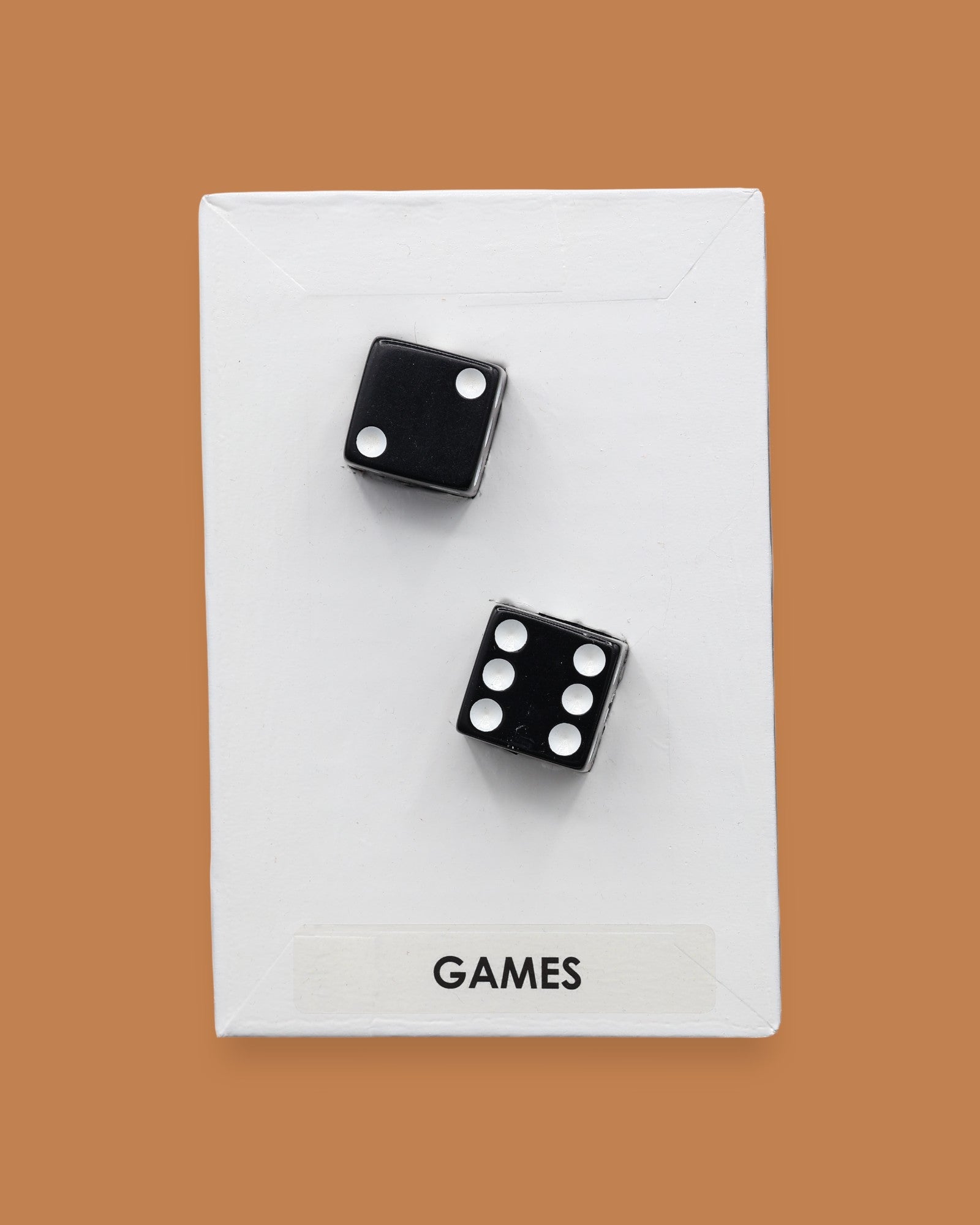 The Games symbol is with two black and white dice embedded diagonally. Labeled "Games" at the bottom of the symbol in black font on a white background. 