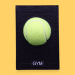 The Gym symbol has a bright yellow tennis ball is centered on a white rectangular surface against a white background. Labeled "Gym" in black font on white backing at the bottom of symbol. The background of the symbol is white.