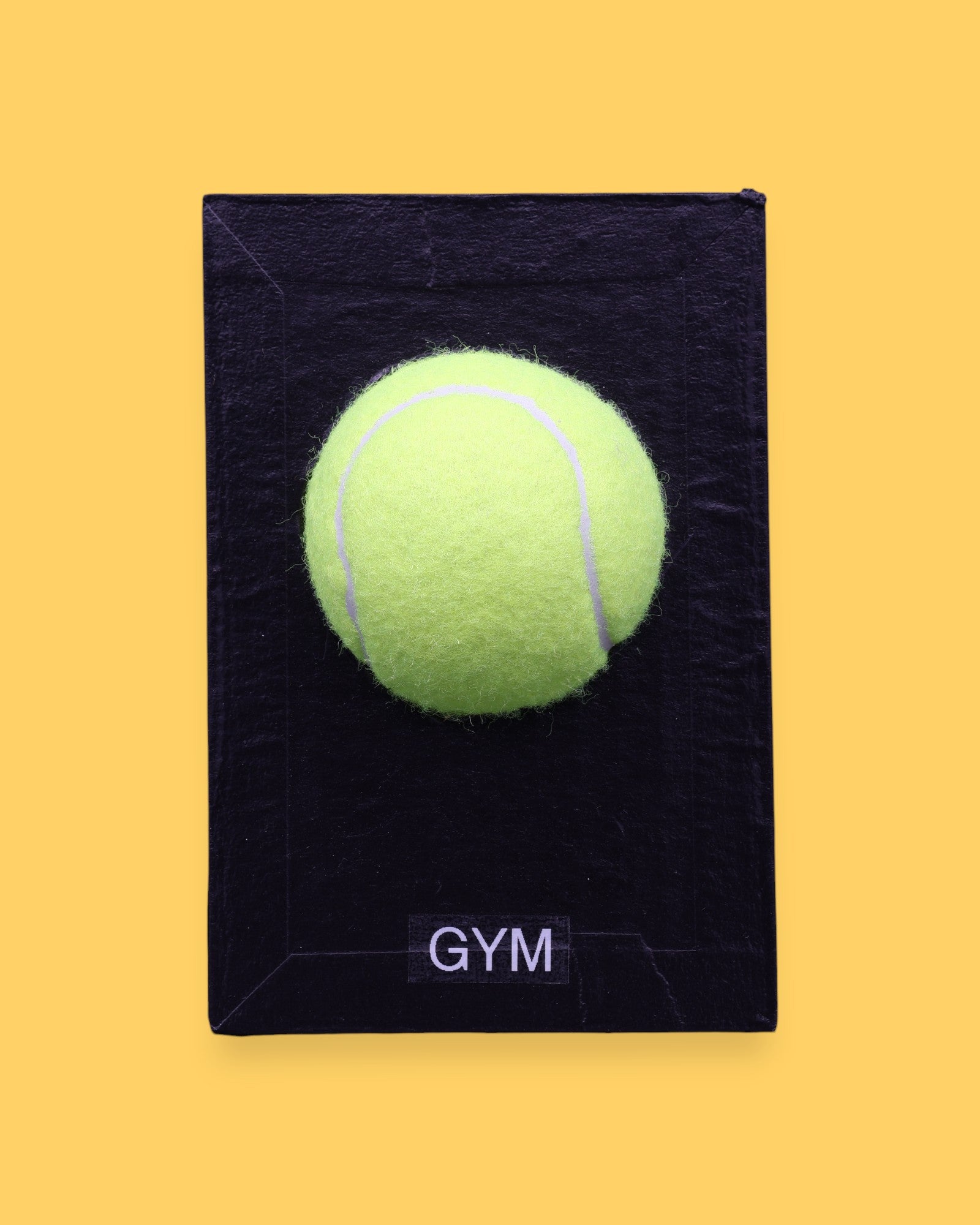 The Gym symbol has a bright yellow tennis ball is centered on a white rectangular surface against a white background. Labeled "Gym" in black font on white backing at the bottom of symbol. The background of the symbol is white.