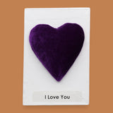 The I Love You symbol with a purple velvet heart attached in the center, labeled "I Love You" in black font at the bottom of symbol on white backing. The background of the symbol is white.