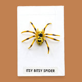 The Itsy Bitsy Spider symbol is a small black toy spider embedded in the center. Labeled "Itsy Bitsy Spider" in black font on white backing at the bottom of the symbol. The background of the symbol is white. 