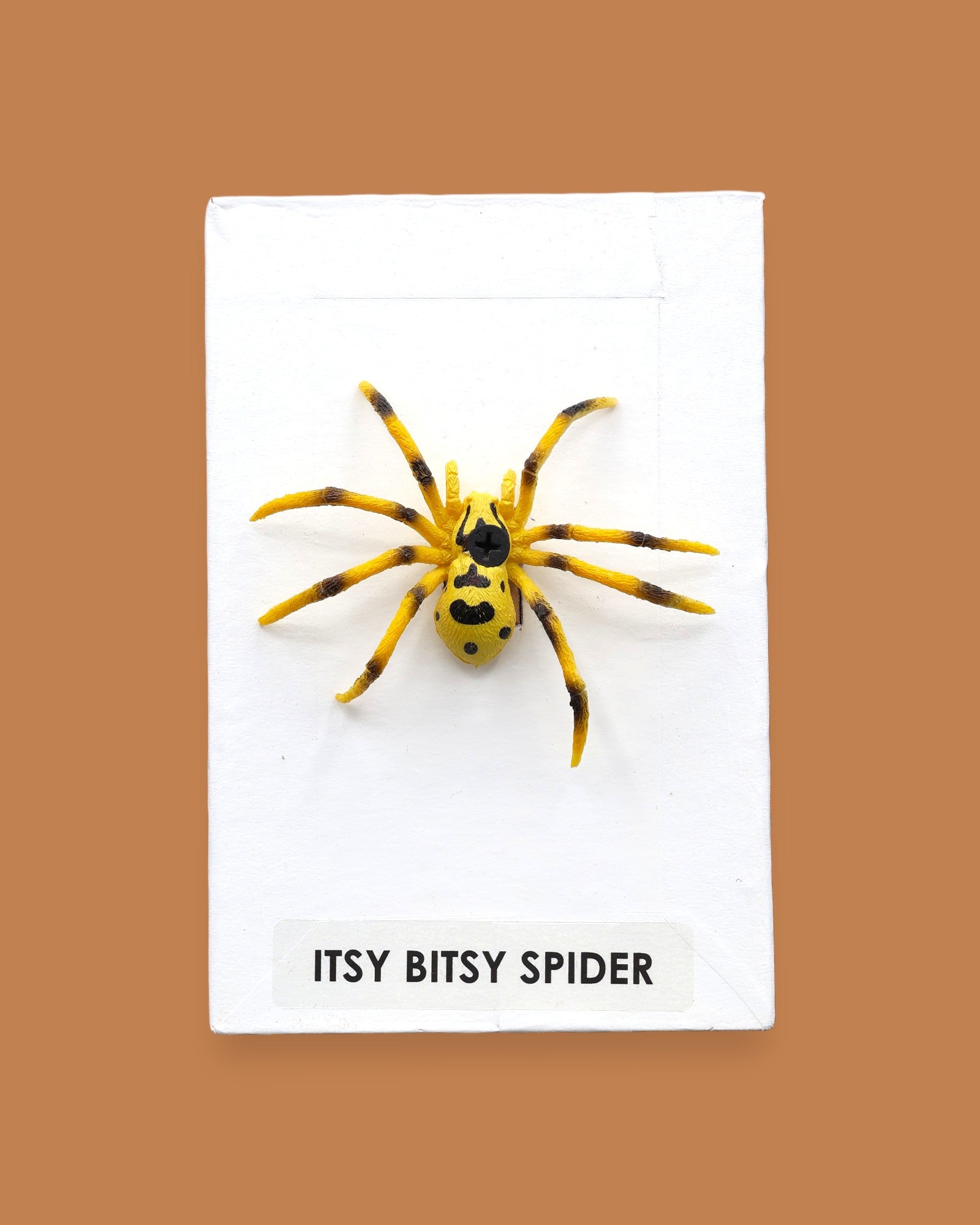 The Itsy Bitsy Spider symbol is a small black toy spider embedded in the center. Labeled "Itsy Bitsy Spider" in black font on white backing at the bottom of the symbol. The background of the symbol is white. 