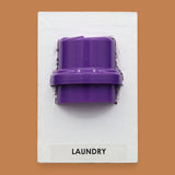 The Laundry symbol cap color may vary. Labeled "Laundry" at the bottom of symbol on a white backing. The background of the symbol is white. If a black backing is requested a high constrast cap color the specific color may vary.