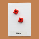 The Math symbol has two colorful square, one orange and one green embedded. Labeled "Math" in black font on white backing at the bottom of symbol. The background of the symbol is white.