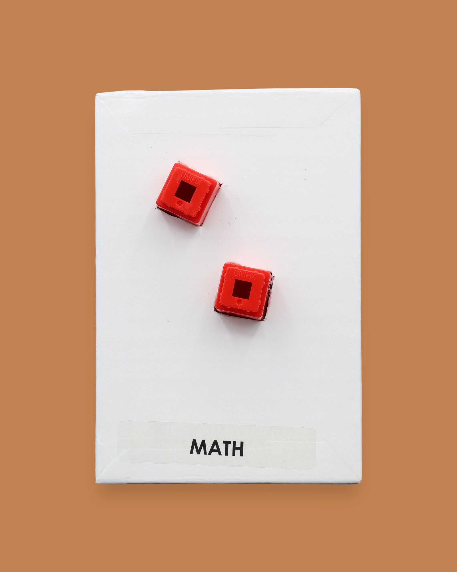 The Math symbol has two colorful square, one orange and one green embedded. Labeled "Math" in black font on white backing at the bottom of symbol. The background of the symbol is white.