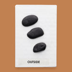 The Outside symbol consists of 3 gray colored real rocks It is composed of real rocks securely embedded diagnolly. Labeled "Outside" in black font and white backing at the bottom of symbol . The background of the symbol is white. 