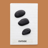 The Outside symbol consists of 3 gray colored real rocks It is composed of real rocks securely embedded diagnolly. Labeled "Outside" in black font and white backing at the bottom of symbol . The background of the symbol is white. 