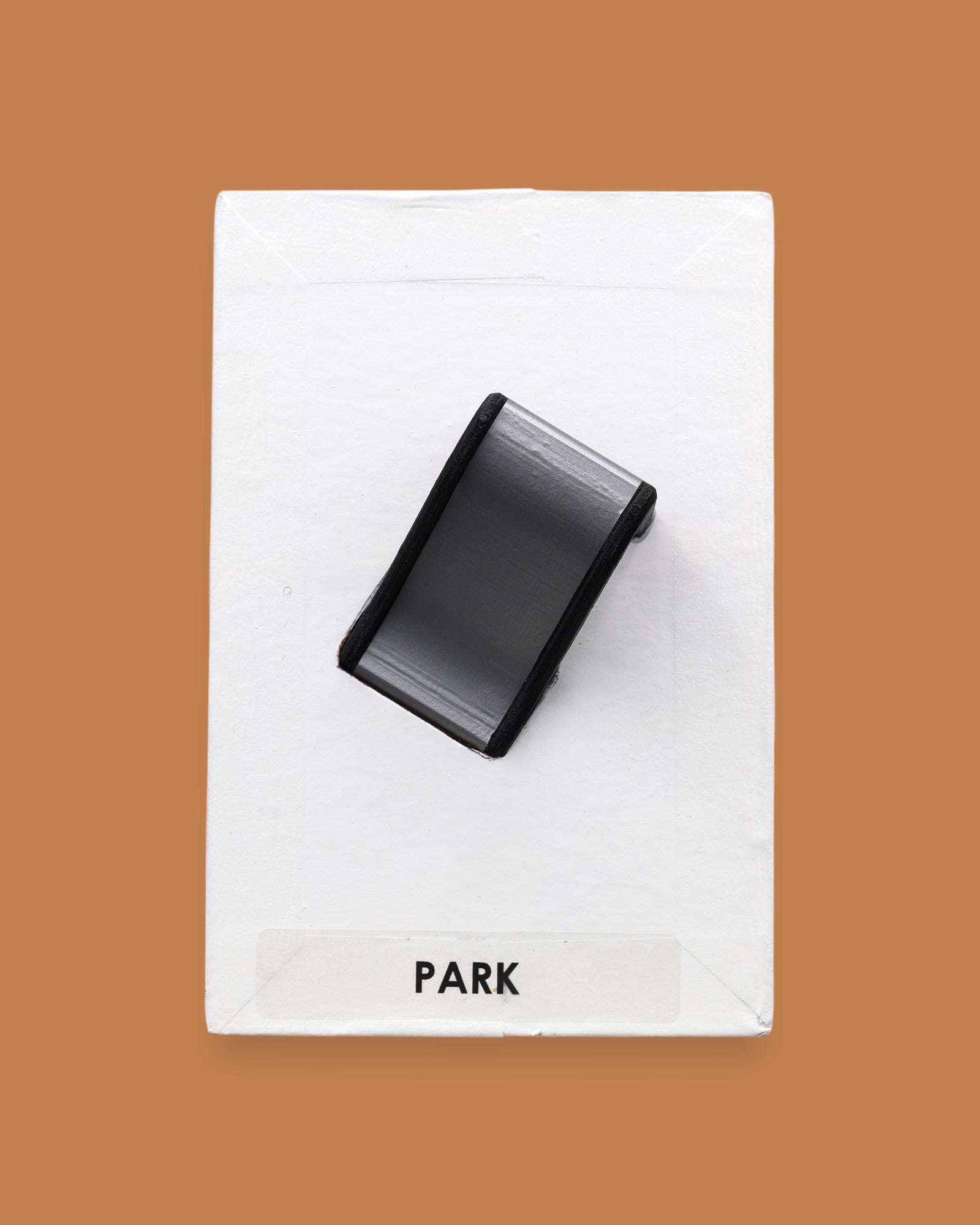 The Park Slide symbol with a small toy shaped slide embedded in the center. Labeled "Park" in black font on white backing at teh bottom of the symbol. The background of the symbol is white. 