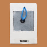 The Science symbol consists of an bright orange 3D printed butterfly ithat s mounted in the center, using PLA 3D printer filament. Labeled "Science" in black font on white backing. The background of the symbol is white. 