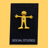 The Social Studies high constrast symbol with a yellow bendy figure embedded in the center. Labeled "Social Studies" in white font at the bottom of symbol on clear backing. The background of the symbol is black. 