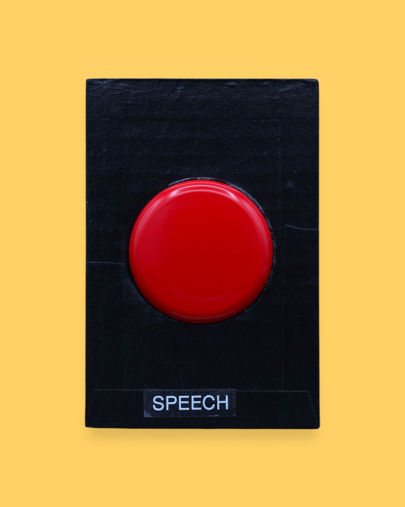 The Speech high contrast symbol with a red switch cap embedded in the center. Labeled "Speech" in white font at the bottom of symbol on clear backing. The background of the symbol is black. 