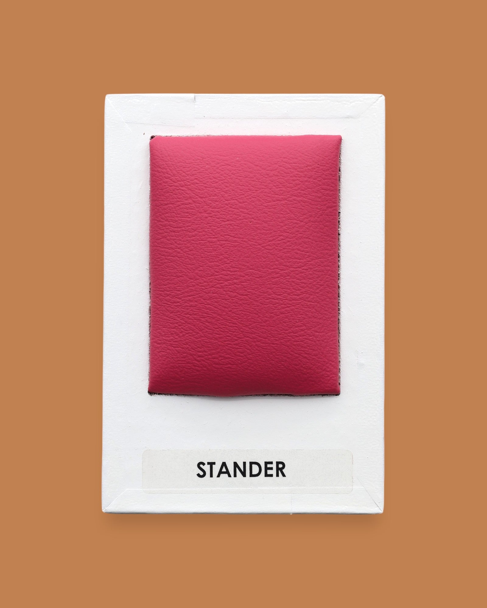 The Stander symbol embedded with a red colored vinyl filled with batton in the center. Labeled "Stander" in black font on white backing at the bottom of the symbol. The background of the symbol is white. 