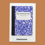 The Classroom symbol has a miniature  small marble composition notebook embedded in the center. Labeled "Classroom" in black font on white backing. The background of the symbol is white. 