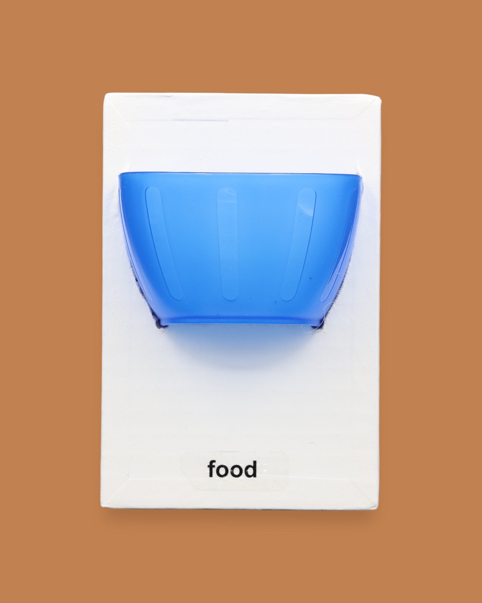 The Food symbol with a small plastic yellow bowl embedded in the center, color of bowl may vary. Labeled "Food" in black font at the bottom of symbol on white backing. 