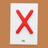 The No symbol with a 3D printed PLA filament with a bright red X embedded in the center. Labeled "No" in black font at the bottom of symbol on white backing. The background of the symbol is white.