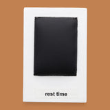 The Rest Time symbol  with a piece of black mat like material embedded in the center. Labeled "Rest Time" in black font on white backing. The background of the symbol is white. 