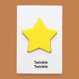 The Twinkle, Twinkle symbol with yellow 3D-printer filament star embedded in the center. Labeled "Twinkle, Twinkle" in black font at the bottom of symbol on white backing. The background of the symbol is white.