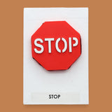 The Stop symbol with a 3D PLA printer filament in a bright red octagonal shape, with white stop lettering embedded in the center. Labeled "Stop" in black font at the bottom of the symbol on white backing. The background of the symbol is white.