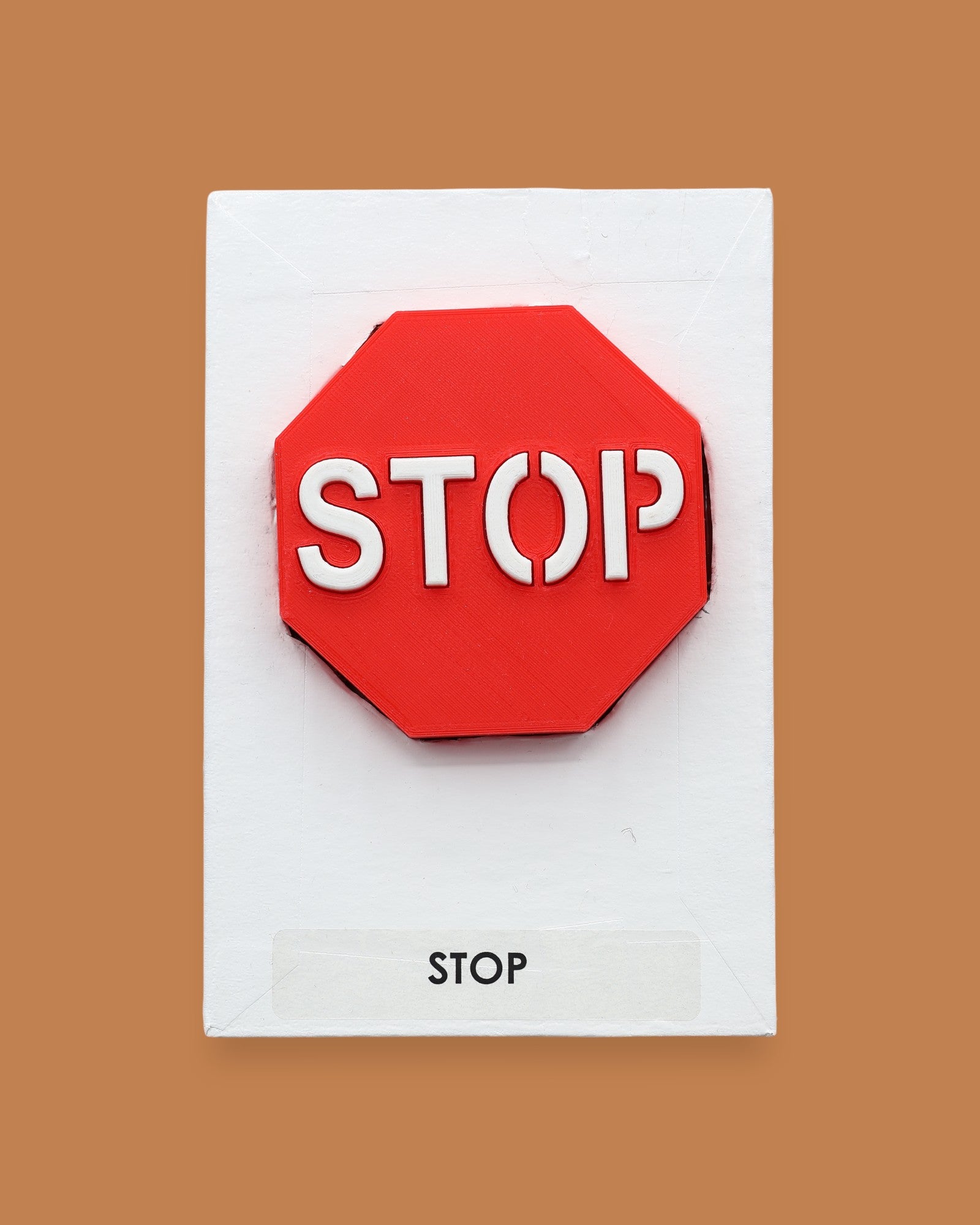The Stop symbol with a 3D PLA printer filament in a bright red octagonal shape, with white stop lettering embedded in the center. Labeled "Stop" in black font at the bottom of the symbol on white backing. The background of the symbol is white.