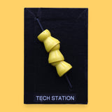 The Tech Station high contrast symbol with a flexible 3 yellow locline pieces embedded vertically. Labeled "Tech Station" in white font at the bottom of symbol on clear backing. The background of the symbol is black. 