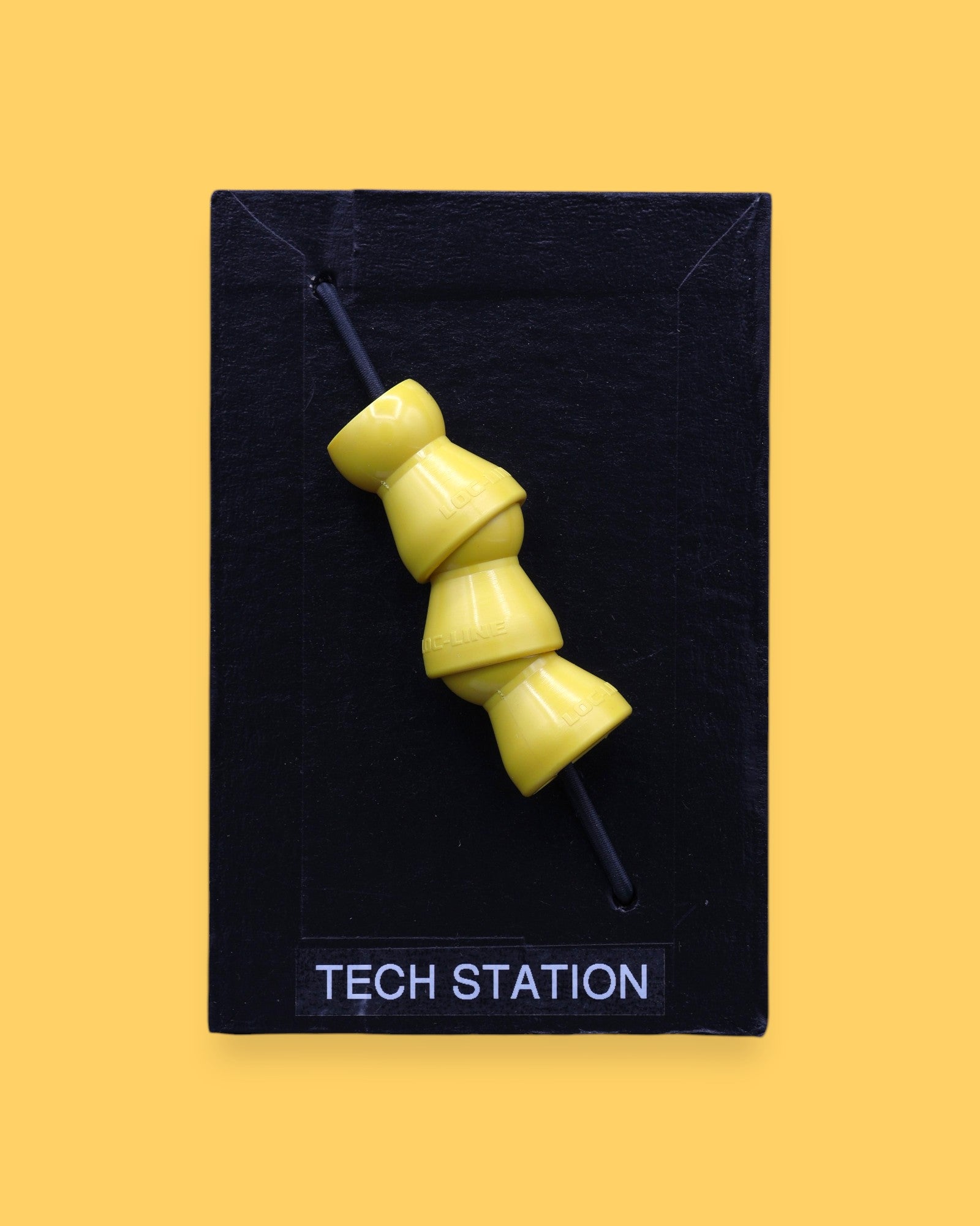 The Tech Station high contrast symbol with a flexible 3 yellow locline pieces embedded vertically. Labeled "Tech Station" in white font at the bottom of symbol on clear backing. The background of the symbol is black. 