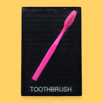 The Toothbrush symbol has a plastic toothbrush is embedded in a diagonal position from the top right corner to the bottom left, with the tactile bristles at the top. Labeled "Toothbrush" in black font on white backing at the bottom of the symbol. The background of the symbol is white. 