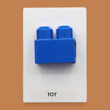 The Toy Big Block symbol with a chuck raised toy-block embedded in the center. Labeled "Toy" in black font on white backing at the bottom of the symbol. The background of the symbol is white. 