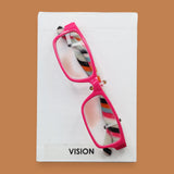 The Vision symbol has plastic eye-glasses of varied colors embedded in the center. Labeled "Vision" in black font and white backing. The background of the symbol is white. 