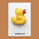 The Water Play symbol embedded with a yellow rubber duck embedded in the center. Labeled "Water Play" in black font on white backing at the bottom of the symbol. Tha background of the symbol is white. 
