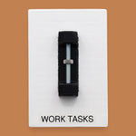 The Work Tasks symbol with an embedded bolt and nut assembly mounted on a black base vertically in the center. Labeled "Work Tasks" in black font on white backing at the bottom of the symbol. The background of the symbol is white. 